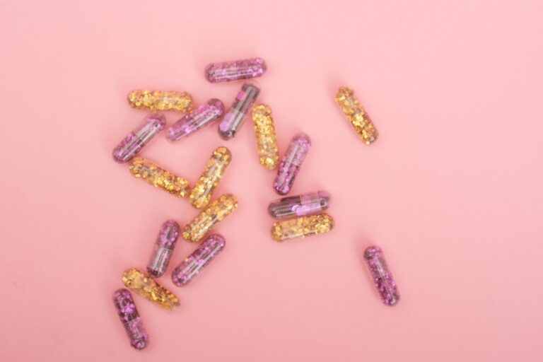 Heap of colorful glitter filled capsules on pink background