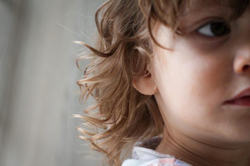 a close up of a child's face with hair blowing in the wind