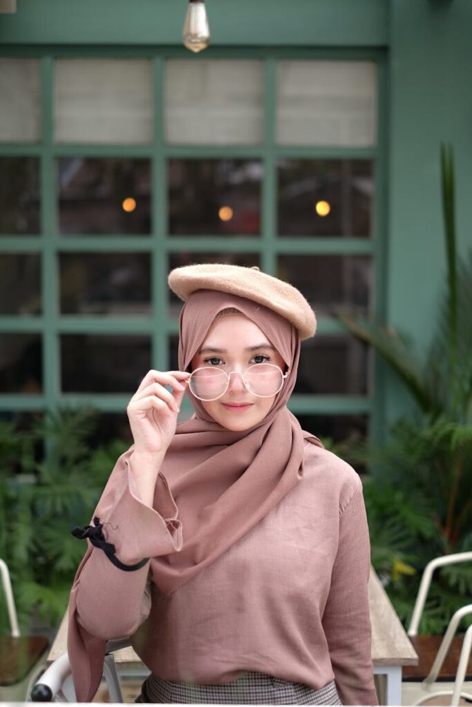 Charming woman wearing hijab and beret, posing elegantly in a modern setting.