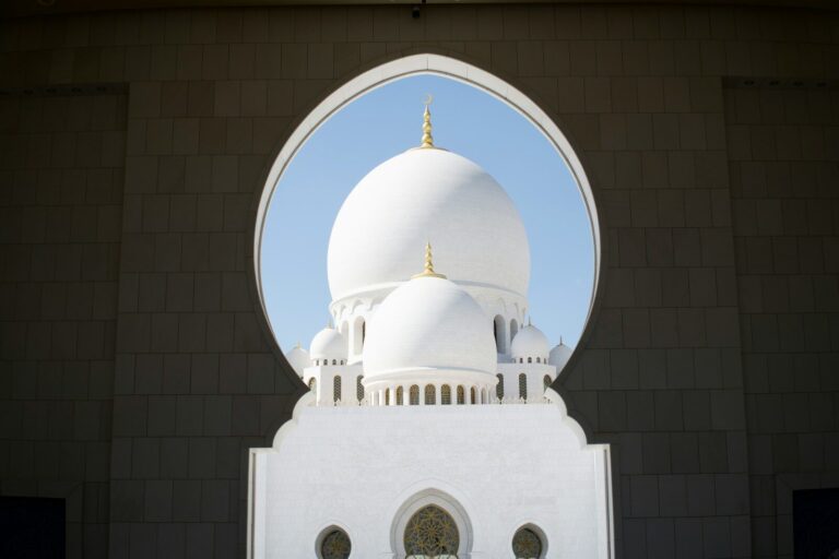 White mosque dome seen through an arched opening