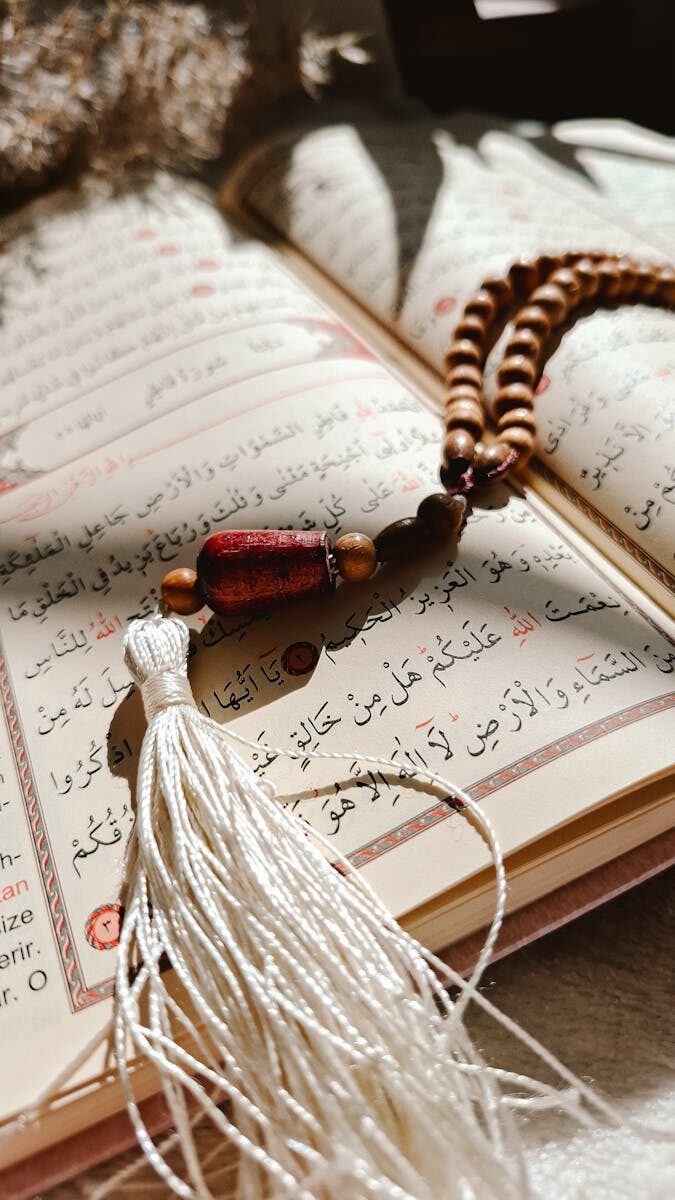 Open Quran with a Misbaha resting on pages under warm sunlight, symbolizing peace and spirituality.
