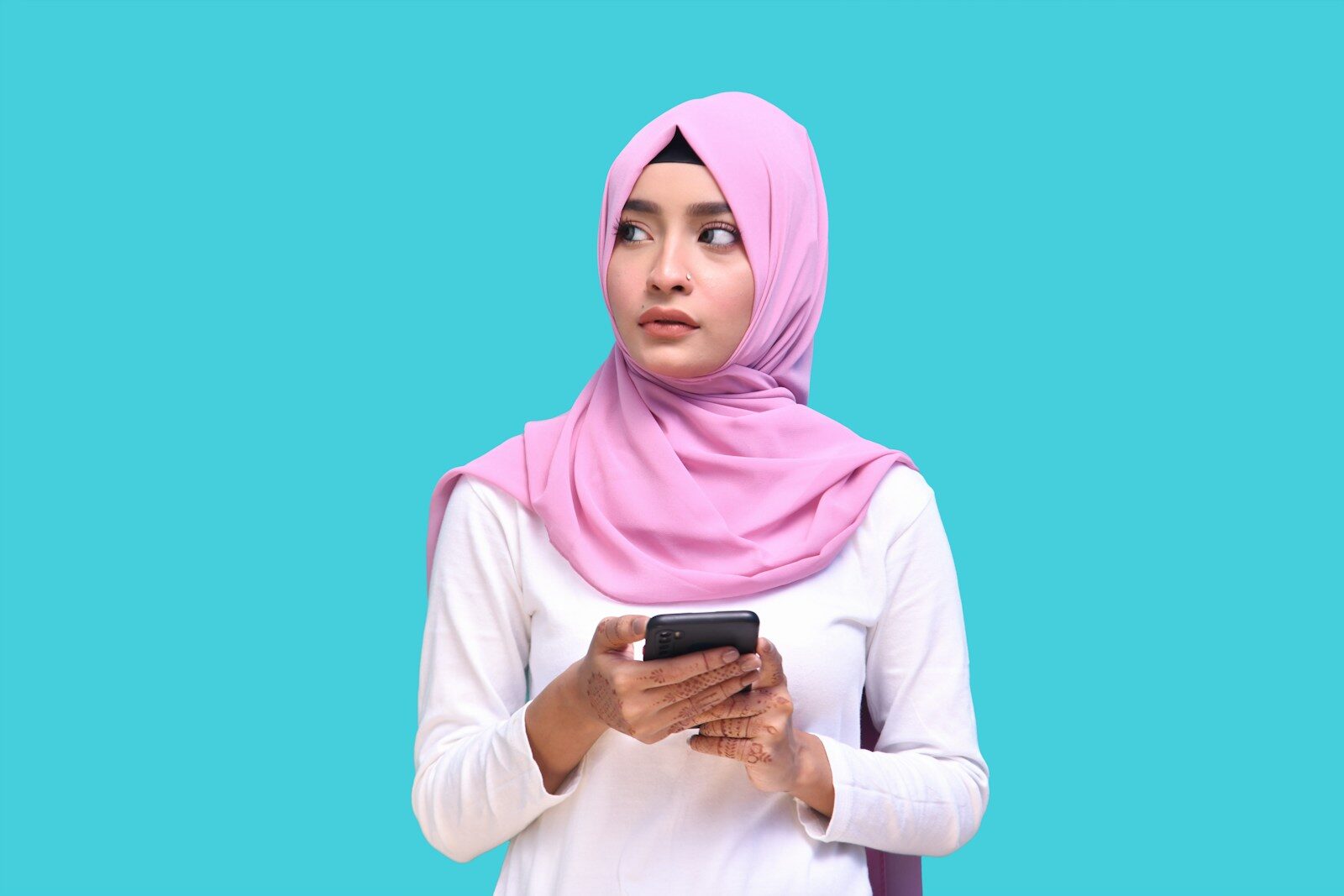 a person wearing a pink head scarf and holding a phone