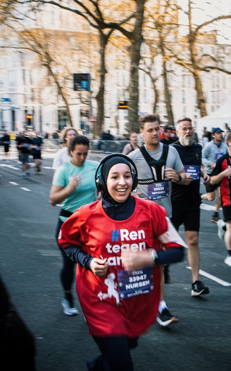 Smiling woman in red shirt running a street marathon.