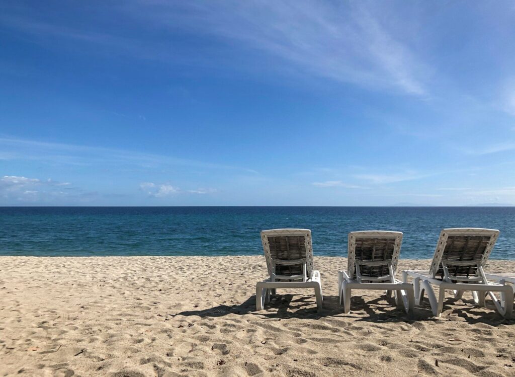 Three empty beach chairs face the ocean.