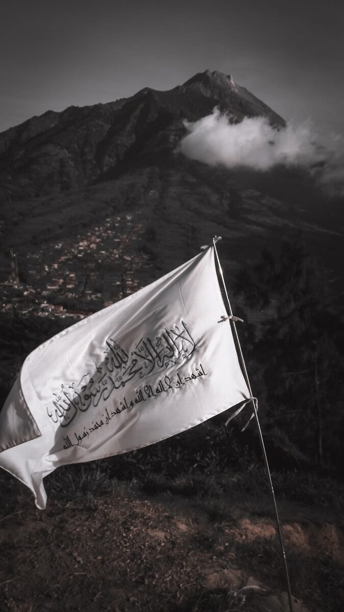 A white flag with black Arabic calligraphy waving before Mount Merbabu in Indonesia
