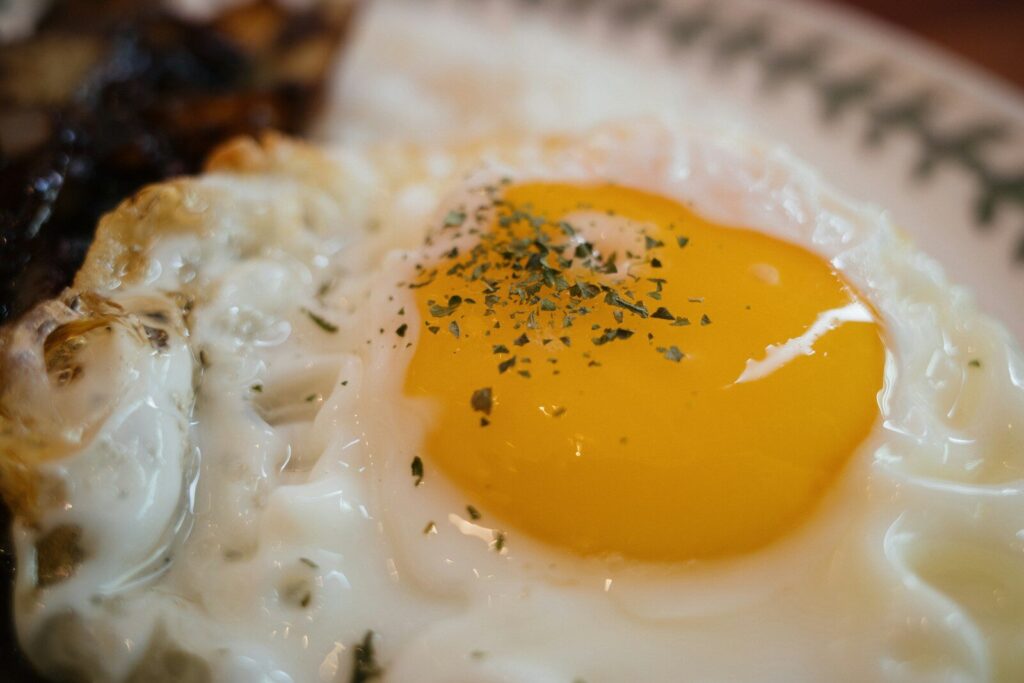 a fried egg on a plate with a side of meat