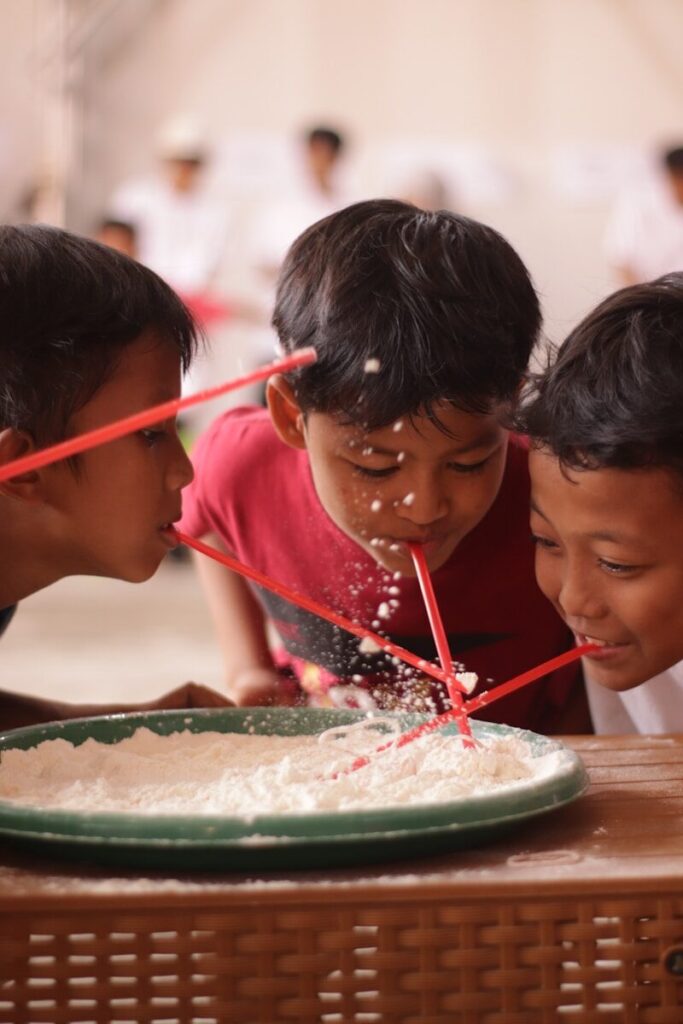 Children playing a game with straws and flour