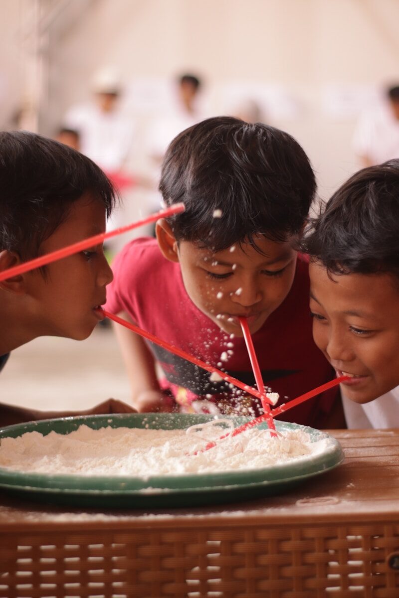 Children playing a game with straws and flour