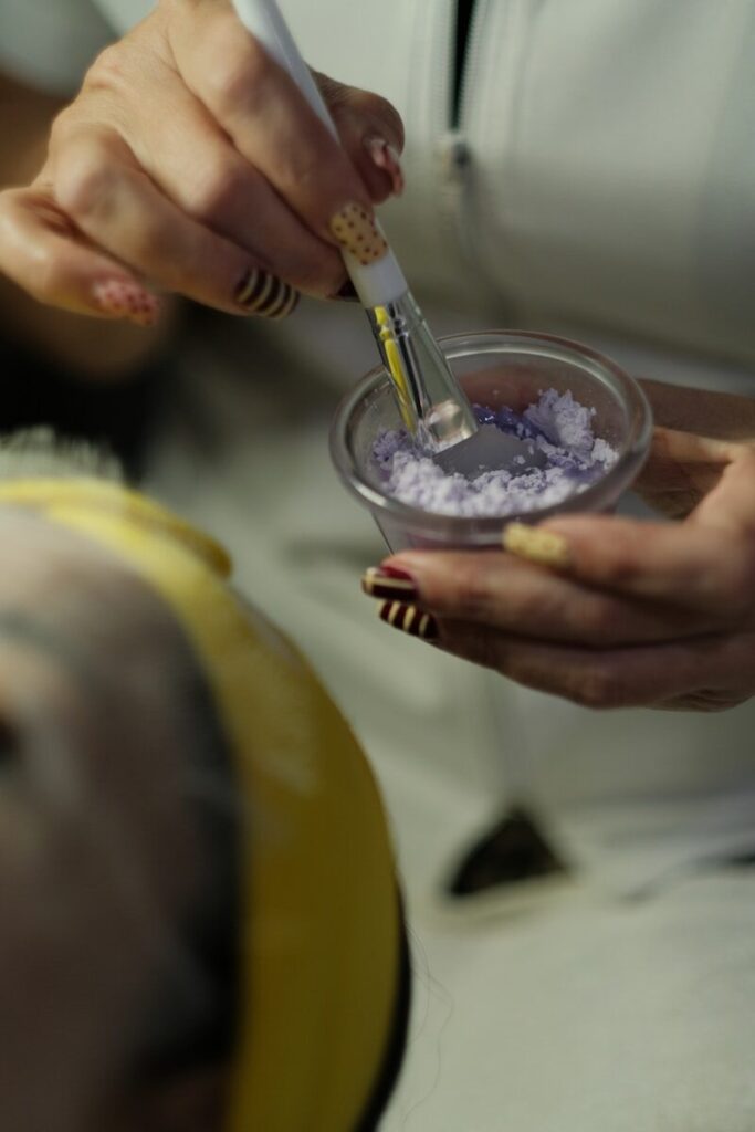 Hands preparing a purple cosmetic mask with a brush