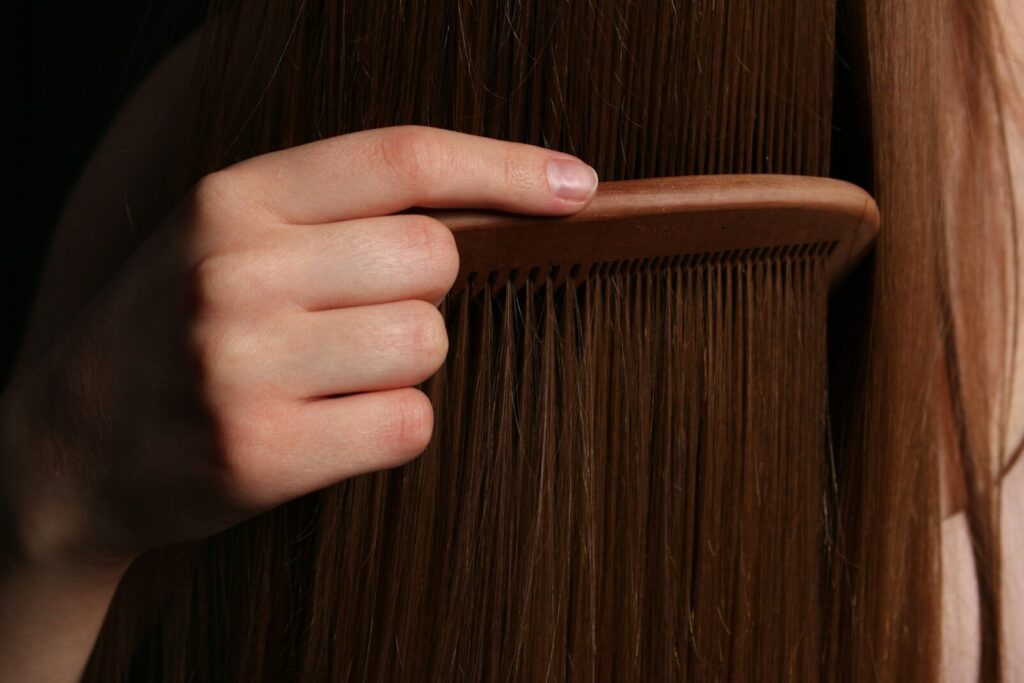 A hand combs long, brown hair