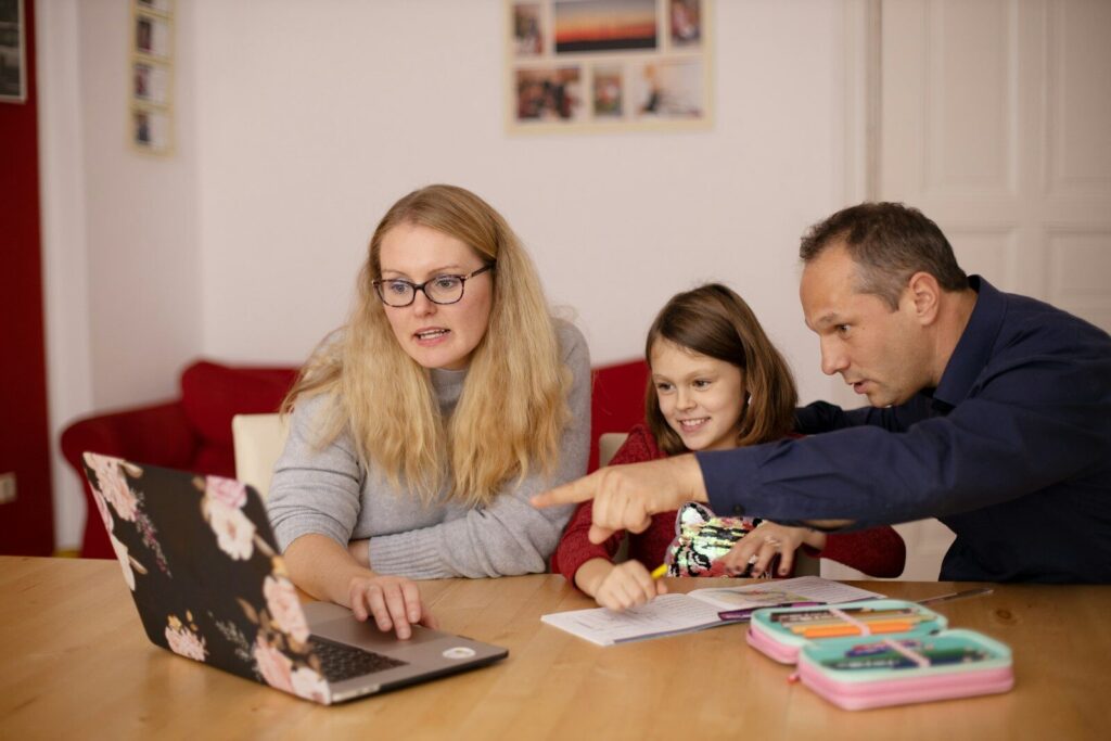 A woman and a man helping a child with schoolwork on a laptop