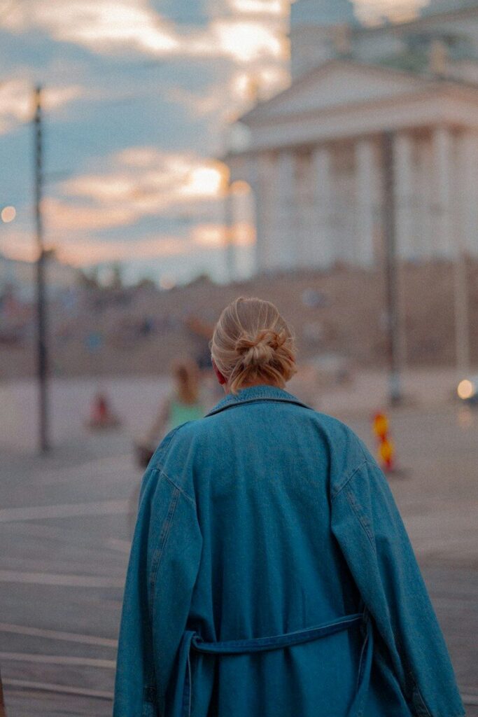 A woman walking down a street past a white building