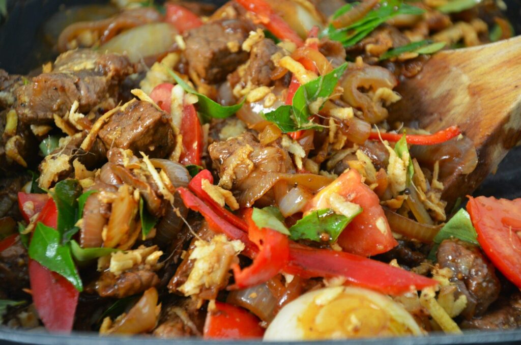A close up of food in a pan with a wooden spoon