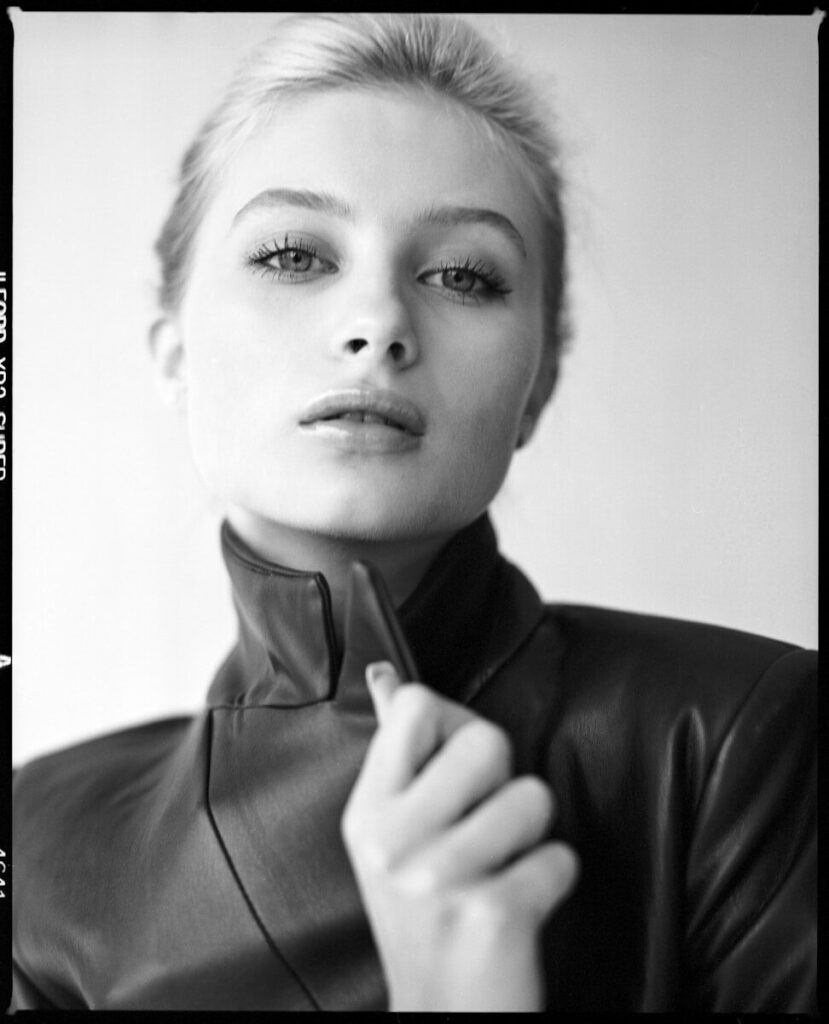 Young woman in dark jacket holding her collar