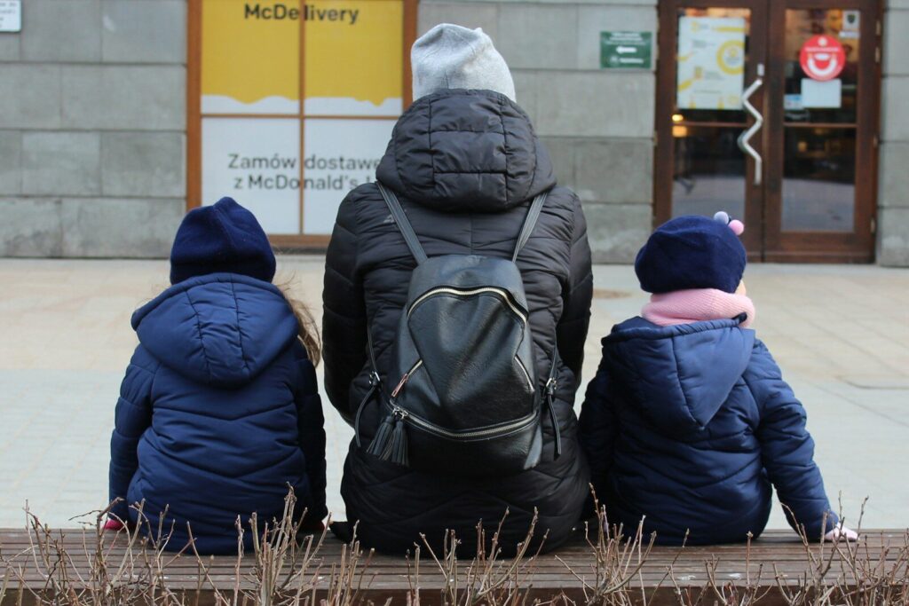 Mother and two children sitting on a bench outside