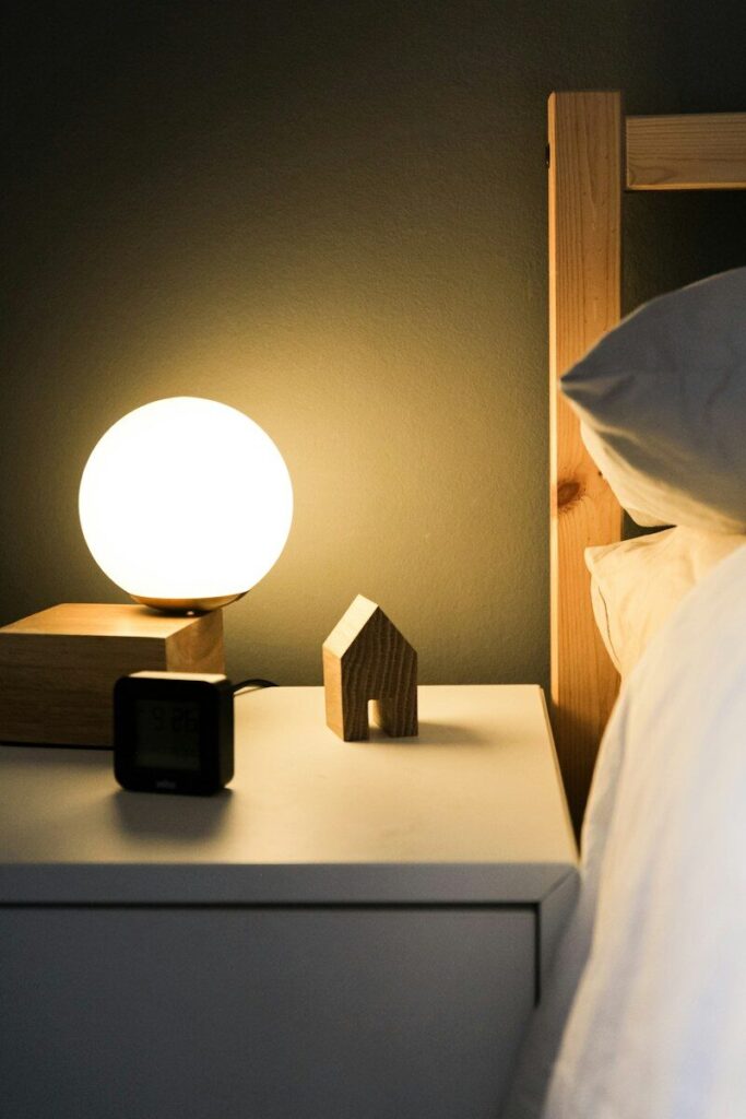A glowing globe lamp, a small wooden house, and a digital clock on a nightstand