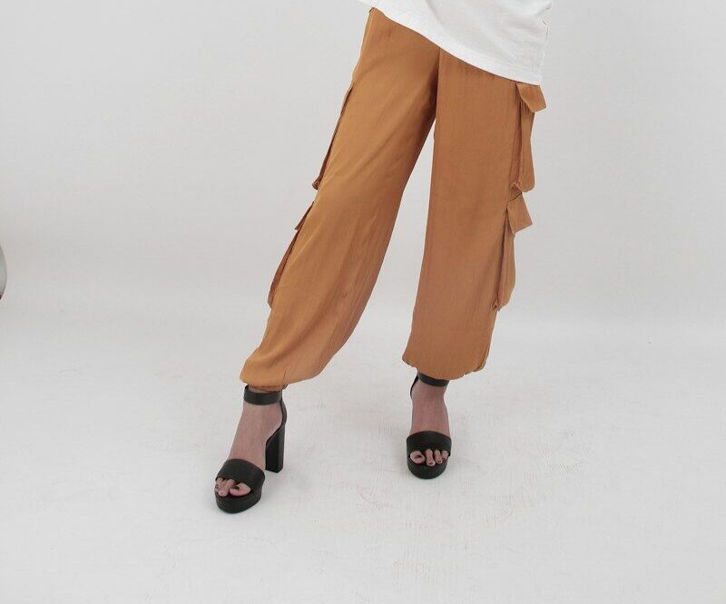 Woman in oversized white tee and orange pants poses