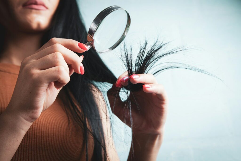 Woman examining split ends of hair with magnifying glass