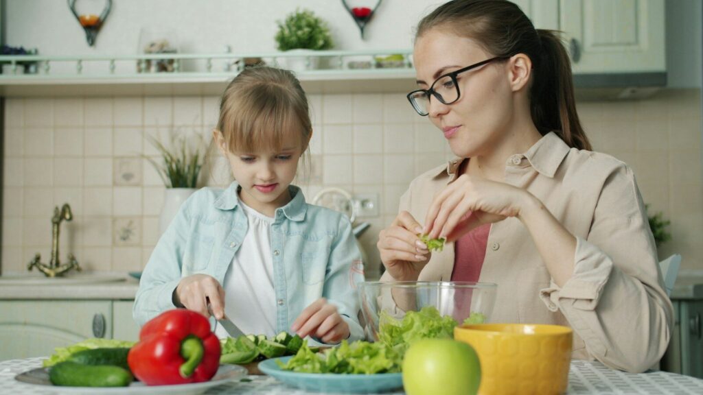 Mother and daughter preparing salad in kitchen