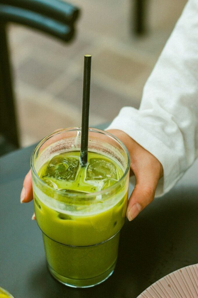 Hand holding a glass of iced matcha latte