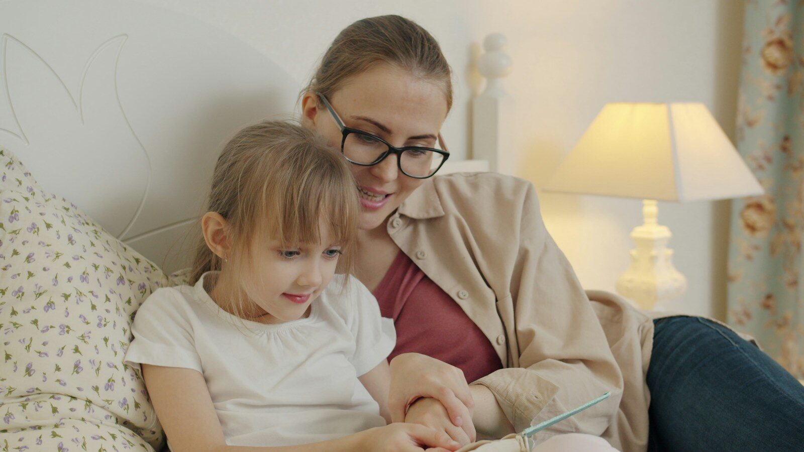 Mother and daughter reading a book in bed